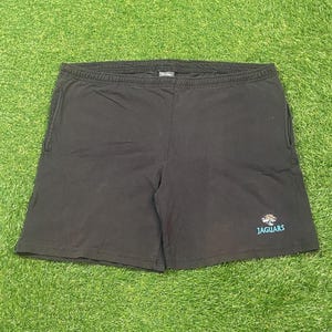 May include: Black athletic shorts with an elastic waistband and pockets. The shorts feature a small logo and the word "JAGUARS" printed in blue. The shorts are made of a soft, comfortable material.