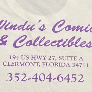 Op de afbeelding: Paarse tekst op een witte achtergrond met de tekst "Windu's Comics & Collectibles", "194 US HWY 27, SUITE A", "CLERMONT, FLORIDA 34711" en "352-404-6452".