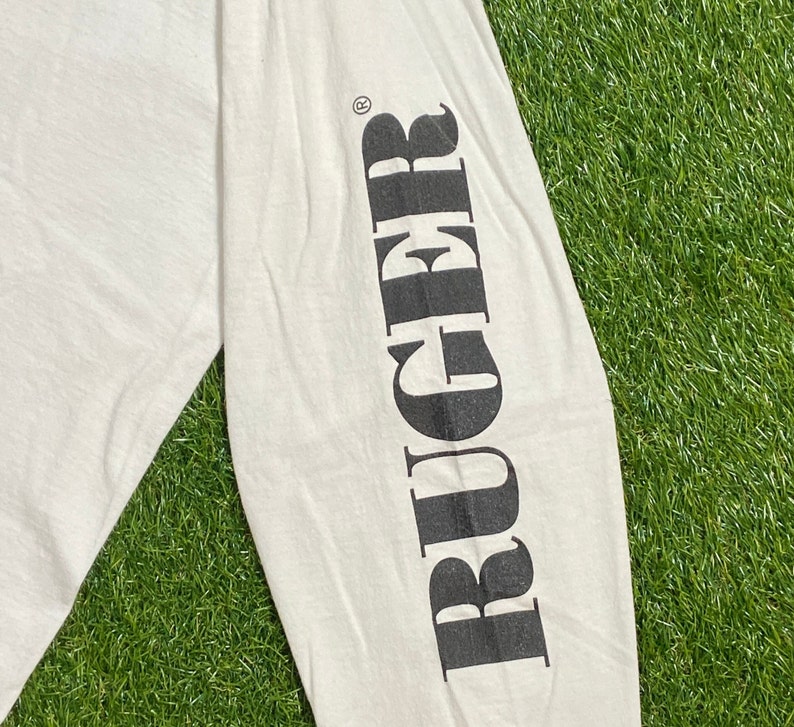 K&ouml;nnte beinhalten: Wei&szlig;es Langarm-T-Shirt mit dem Wort "RUGGER" in Schwarz auf dem linken &Auml;rmel.