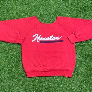 May include: Red sweatshirt with a white "Houston" graphic on the front.