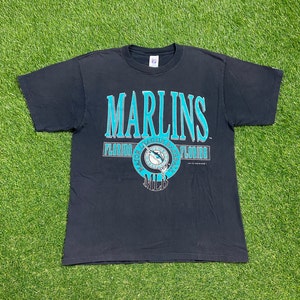 May include: Black t-shirt with a teal blue graphic of the Florida Marlins logo. The logo features a marlin fish, the words "Florida Marlins Baseball", and "MLB".