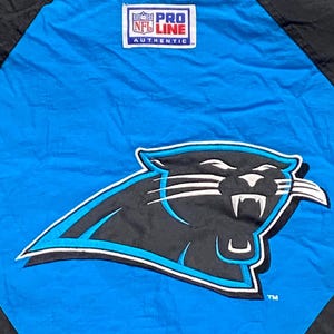 Peut inclure: Veste bleue et noire avec le logo des Panthers de la Caroline. Le logo est une panth&egrave;re noire avec des accents blancs et un contour bleu. La veste porte un &eacute;cusson "Pro Line NFL Authentic".