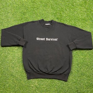 May include: Black sweatshirt with the text "Street Survival" printed in silver on the front.