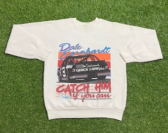 May include: White long-sleeve sweatshirt with a black and red graphic of a race car with the text "Dale Earnhardt" and "Catch Him If You Can".