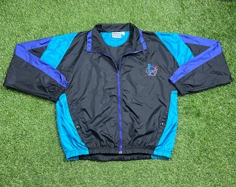 May include: A black, blue, and purple windbreaker jacket with a zipper closure. The jacket has a logo on the left chest that says "Wildfire" and a graphic design on the right chest.