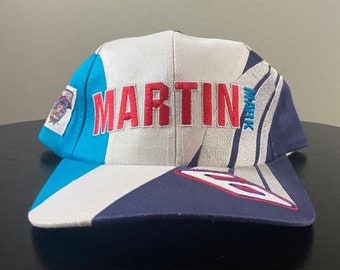 Könnte beinhalten: Eine blaue, weiße und marineblaue Baseballkappe mit dem Wort "MARTIN" in rot auf der Vorderseite gestickt. Die Kappe hat ein weiß-blaues Streifenmuster an der Seite.