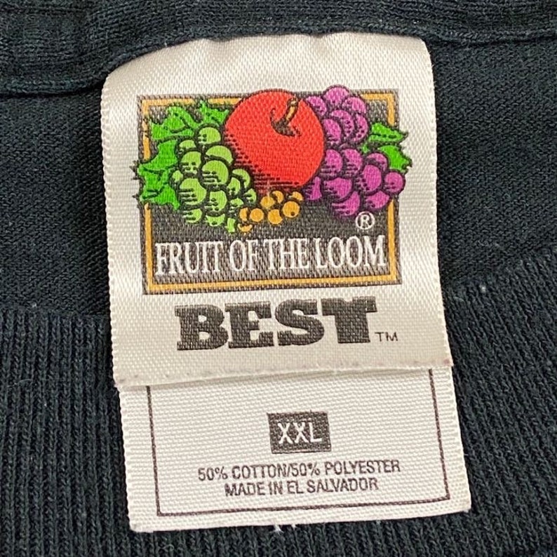 Może przedstawiać: Czarna metka koszulki Fruit of the Loom Best z logo czerwonego jabłka i fioletowych winogron. Metka zawiera napis "XXL", "50% Bawełna/50% Poliester" i "Wyprodukowano w Salwadorze".