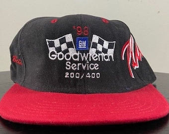 Könnte beinhalten: Eine schwarze und rote Baseballkappe mit einem weißen und schwarzen kariert-Flaggen-Design. Die Kappe hat den Text "Goodwrench Service 200/400" und "'98 GM" aufgestickt.