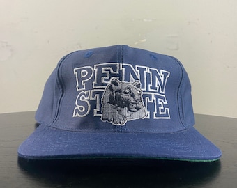 May include: A navy blue baseball cap with a white embroidered logo that says "Penn State" and features a cartoon Nittany Lion mascot.