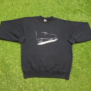May include: Black sweatshirt with a white outline of an ice skate on the front.