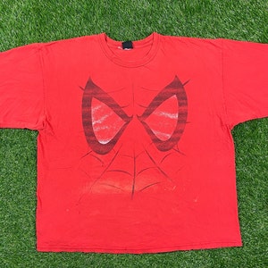 Puede incluir: Camiseta roja con un estampado gr&aacute;fico de la cara de Spider-Man. El dise&ntilde;o es en negro y rojo y presenta los ojos y la telara&ntilde;a de Spider-Man.