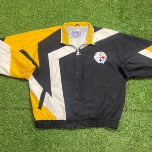 May include: A black, yellow, and white zip-up windbreaker jacket featuring the Pittsburgh Steelers logo on the left chest. The jacket has a high collar, long sleeves with elastic cuffs, and a Starter brand zipper pull. The interior tag reads Pro Line.