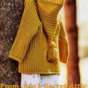 Peut inclure: Un sweat à capuche en tricot jaune avec un pompon sur la capuche. Le sweat est suspendu à un tronc d'arbre. De Jojo's Secret Attic.