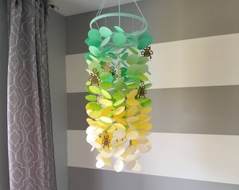 Baby mobile in turquoise, lime green, yellow and white with kraft brown monkeys. Decoration for children's nursery. Decorative paper mobile.