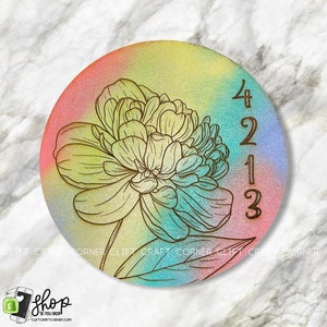 K&ouml;nnte beinhalten: Ein runder Untersetzer aus Holz mit einem farbenfrohen Ombre-Design in den Farben Rosa, Gelb, Blau und Gr&uuml;n. Ein Blumenmuster ist in den Untersetzer ge&auml;tzt, ebenso die Zahlen 4213.