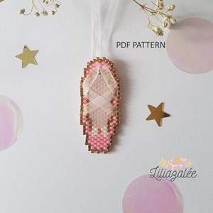 May include: A pink and white beaded ballerina shoe charm with gold accents. The charm is hanging from a white ribbon. The image includes the text "PDF PATTERN".