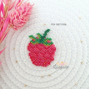 May include: A beaded strawberry charm with a green stem and leaves. The charm is made with red, green, and yellow beads. The charm is on a white background with the text "PDF PATTERN" and "Liliazalee".