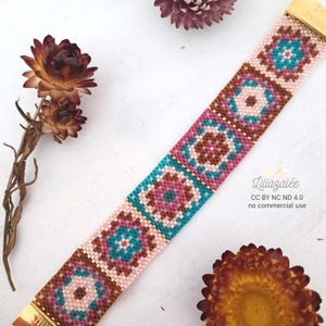 May include: A colourful beaded bracelet featuring a geometric design in pink, brown, and teal. The bracelet has a gold clasp and is decorated with dried flowers. The text "LiliaZalee" is visible.