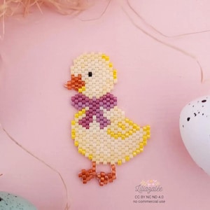 May include: A beaded yellow chick with a purple bow tie, orange beak and feet. The chick is made of small beads and is set against a pink background with decorative elements. The image includes text.