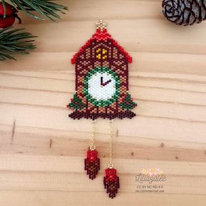 May include: A handcrafted beaded cuckoo clock ornament. The clock features a red roof, a white clock face, and decorative green and red accents. Two beaded weights hang below the clock on gold chains. The ornament is set against a wooden background.