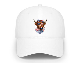 Op de afbeelding: Witte baseballcap met een afbeelding van een Schotse Hooglander die een zonnebril en een patriottische bandana draagt. De koe heeft een rood, wit en blauw vuurwerkontwerp en de tekst "Red, White & Moo".