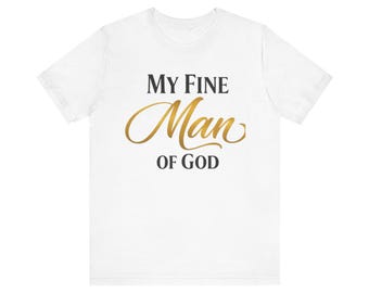 Op de afbeelding: Wit T-shirt met de tekst "MY FINE Man OF GOD" in zwarte en gouden letters. Het shirt heeft een ronde hals en korte mouwen. De tekst staat in het midden van de voorkant van het shirt.