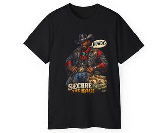 Op de afbeelding: Zwart t-shirt met een cowboy-illustratie. De cowboy draagt een hoed, leren jas en een rood geruit overhemd. De tekst "HOWDY!" staat in een tekstballon en "SECURE THE BAG!" staat onder de cowboy en de geldbuidels.