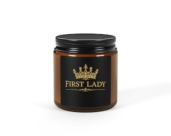 Op de afbeelding: Een bruine glazen pot met een zwart deksel. De pot heeft een zwart etiket met gouden tekst "FIRST LADY" boven een gouden kroonontwerp. De pot staat op een witte ondergrond.