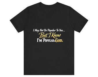 Op de afbeelding: Zwart T-shirt met de tekst "I May Not Be Popular To You... But I Know I'M POPULAR TO GOD." in witte en gele letters. Het shirt heeft een ronde hals en is geschikt voor casual wear.