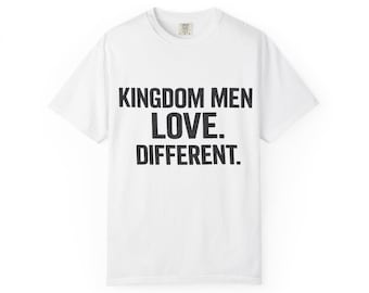 Op de afbeelding: Wit t-shirt met de tekst "KINGDOM MEN LOVE. DIFFERENT." in vette, zwarte letters. Het shirt heeft een ronde hals en korte mouwen. De stof lijkt een zachte katoenmix te zijn.