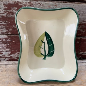 May include: A white ceramic baking dish with a green rim and a green and yellow leaf design.