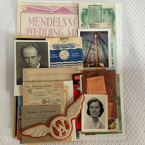May include: A collection of vintage ephemera including a Mendelssohn Wedding March program, a View-Master reel, a black and white portrait of a man, an American Legion document from 1939, a ship photograph, a calendar, and a winged WA embroidered patch.