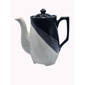 May include: A black and white ceramic teapot with a geometric design. The teapot has a black lid and a white handle.
