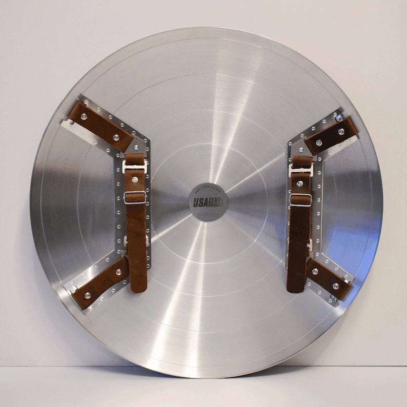 May include: A silver metal Captain America shield with brown leather straps and the text "USAGENT" on the front.