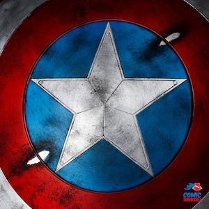 Puede incluir: Un escudo de bandera americana rojo, blanco y azul con una gran estrella plateada de cinco puntas en el centro. El escudo est&aacute; desgastado y deteriorado, con ara&ntilde;azos y rozaduras visibles.