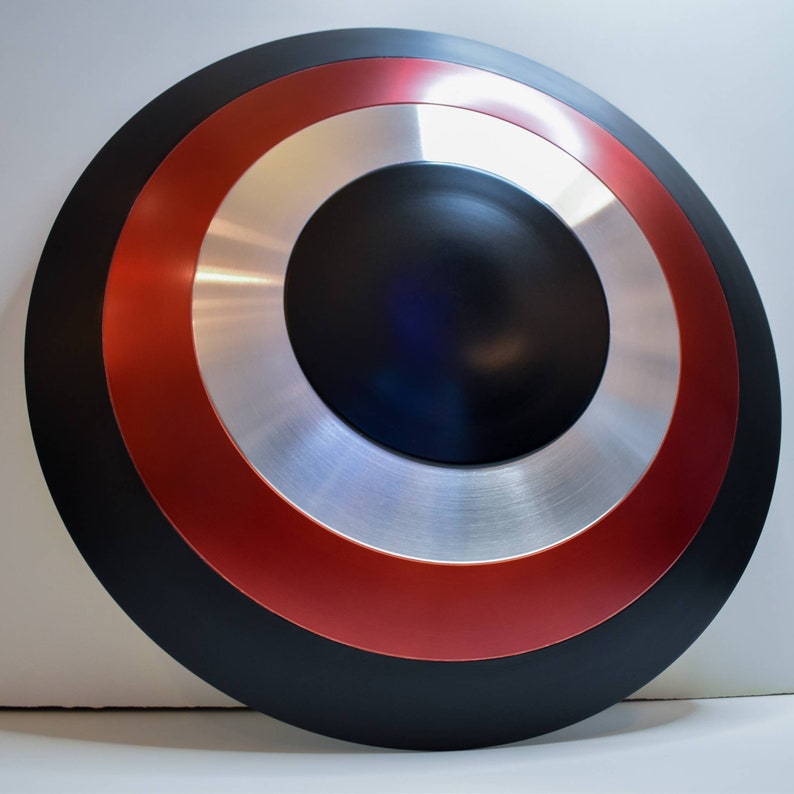 May include: A black, red, and silver Captain America shield replica. The shield is round and has a raised center.