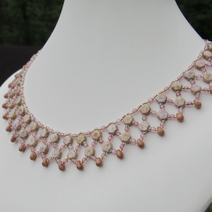 May include: A delicate pink and brown beaded necklace with a cascading design. The necklace is made with small, round beads and features a subtle floral pattern.