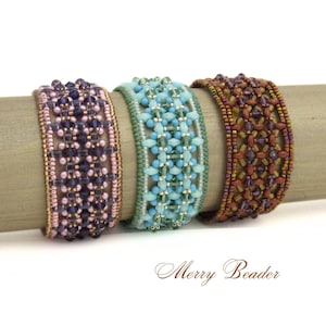 May include: Three beaded bracelets in shades of purple, teal, and brown are displayed on a wooden dowel. The bracelets feature intricate patterns of beads in various sizes and colors. The text "Merry Beader" is at the bottom.