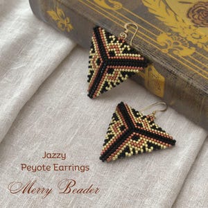 Può includere: Orecchini triangolari di perline con un motivo geometrico nei colori nero, oro e rame. Gli orecchini hanno ganci per le orecchie color oro. Il testo "Jazzy Peyote Earrings" e "Merry Beader" sono visibili.