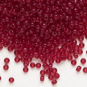 May include: A pile of small, translucent, dark red glass beads. The beads are round with a hole through the center, and are scattered across a white surface. These beads are suitable for jewelry making and crafts.