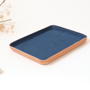 Grand plateau de voiturier en cuir. Intérieur en daim bleu marine. Idéal pour ranger vos essentiels du quotidien tels que clés, lunettes, pièces de monnaie, montres et portefeuilles