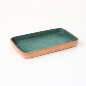 Bandeja de cuero para valet mediano. Interior de gamuza verde bosque. Perfecta para guardar objetos esenciales de uso diario, como llaves, gafas, relojes y billeteras.