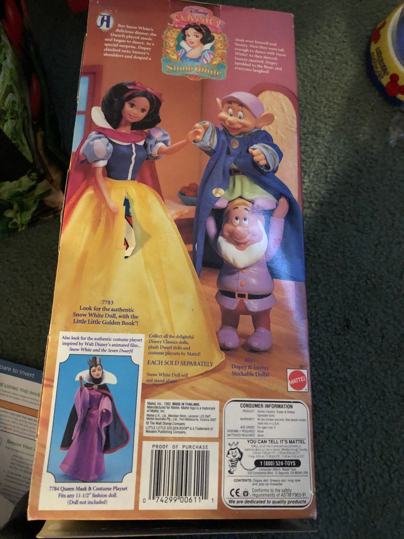 Puede incluir: Una caja para un juego de mu&ntilde;ecas de Blancanieves con una imagen de Blancanieves y Dopey. La caja es amarilla y presenta una imagen de Blancanieves y Dopey. La caja tambi&eacute;n incluye una imagen de la Reina Malvada. La caja est&aacute; etiquetada como "Disney Classics" y "Blancanieves".