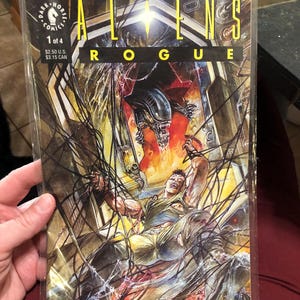 May include: A comic book cover featuring an alien creature with sharp teeth and claws, attacking a human character. The cover is titled "Aliens Rogue" and is issue number 1 of 4. The comic book is published by Dark Horse Comics.