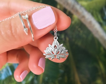 May include: A silver necklace with a delicate lotus flower pendant. The pendant is detailed and intricate, with a floral design.