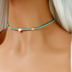 May include: A turquoise and white beaded choker necklace with a white shell charm.