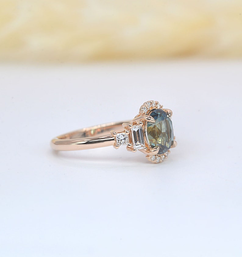 Teal sapphire and baguette diamond cluster engagement ring

 Teal sapphire 
 Approx. 8.35mm x 6.08 mm oval shape
 1.50ct


 Color G and clarity VS quality
 2 x 2mm princess cut 2 pcs
 2 x 4mm baguette cut 2pcs
 1.5mm Round brilliant-cut 8 pcs