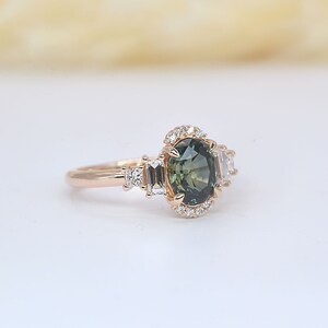 Teal sapphire and baguette diamond cluster engagement ring

 Teal sapphire 
 Approx. 8.35mm x 6.08 mm oval shape
 1.50ct


 Color G and clarity VS quality
 2 x 2mm princess cut 2 pcs
 2 x 4mm baguette cut 2pcs
 1.5mm Round brilliant-cut 8 pcs