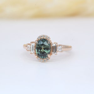 teal sapphire diamond cluster ring

 Teal sapphire 
 Approx. 8.35mm x 6.08 mm oval shape
 1.50ct


 Color G and clarity VS quality
 2 x 2mm princess cut 2 pcs
 2 x 4mm baguette cut 2pcs
 1.5mm Round brilliant-cut 8 pcs