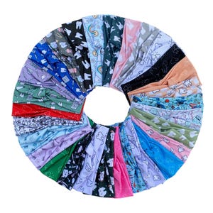 May include: A circular arrangement of colorful headbands with various dental-themed patterns. The headbands feature designs of teeth, dental tools, and smiling faces in a variety of colors, including blue, pink, green, and black. The headbands are made of a soft, flexible material.